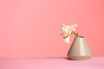 Fototapeta na wymiar Stylish vase with beautiful flower on table against color background, space for text