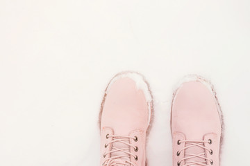 Female legs in pink boots in the snow