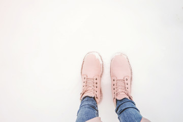 Female legs in pink boots in the snow