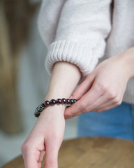 a bracelet of stones (garnet), bracelet of dark red, black stones on the hand, the girl touches the stones on the bracelet (close up, vertically).