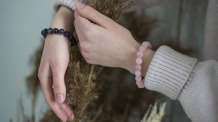 bracelets of purple and pink stones on the hand, in the hands of dried flowers, bracelets of amethyst and rose quartz