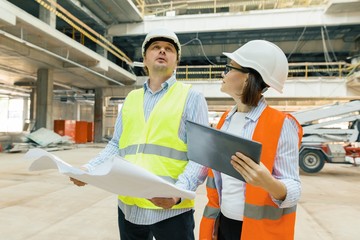 Building workers working at construction site, builders looking in blueprint. Building, development, teamwork and people concept