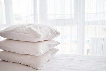 Fototapeta na wymiar Stack of white soft pillows on comfortable bed sheet with window on background, copy space