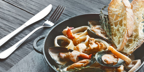 Seafood Stew in Saucepan closeup on dark wood background