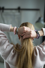 the girl straightens her blonde hair, bracelets of amethyst, rose quartz, tourmaline quartz, sherl, charoite