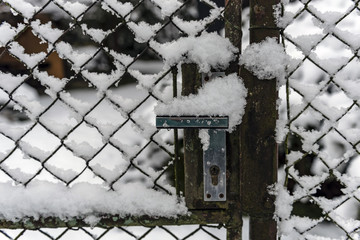 detail of the crank of the garden gate covered with snow in the winter landscape