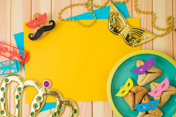 Jewish holiday Purim background with cute funny  hamantaschen cookies and paper note on wooden table.