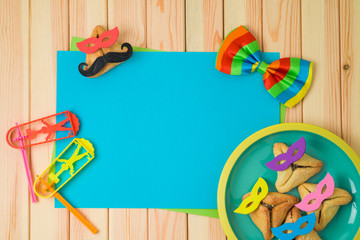 Jewish holiday Purim background with cute funny  hamantaschen cookies and paper note on wooden table.