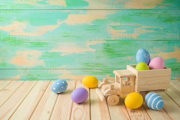 Easter holiday background with easter eggs and toy truck on wooden table