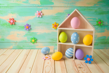 Easter holiday background with easter eggs iand toy house on wooden table