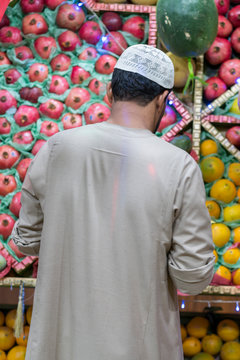 Unidentified Arabian man on the street sell local vegetable and fruits. man selling vegetables on a market. Arab man in the bazaar. vertical photo