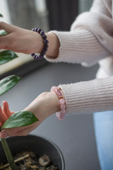the girl has rose quartz and amethyst bracelets, the girl is holding a branch with green leaves.
