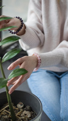 the girl is holding a branch with green leaves, the girl has rose quartz bracelets.