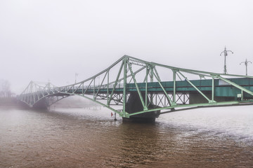 An old bridge is visible across the canal mist
