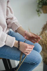 a girl with rose quartz and amethyst bracelets holding a branch of dry grass.