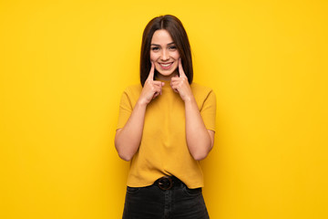 Young woman over yellow wall smiling with a happy and pleasant expression
