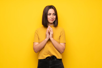 Young woman over yellow wall scheming something