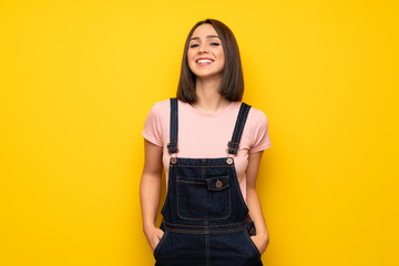 Young woman over yellow wall smiling a lot