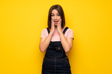 Young woman over yellow wall with surprise facial expression