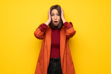 Young woman with coat surprised and shocked while looking right