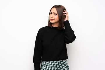 Young woman over white wall having doubts while scratching head