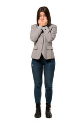 A full-length shot of a Young business woman nervous and scared putting hands to mouth over isolated white background