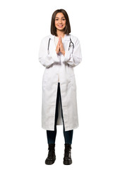 A full-length shot of a Young doctor woman keeps palm together. Person asks for something over isolated white background