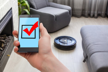 Robotic vacuum cleaner working and a man hold the remote controller