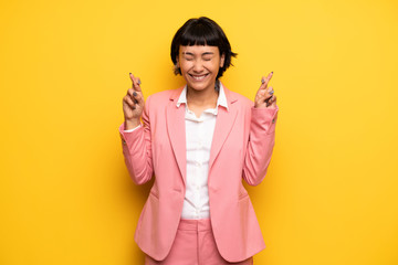 Modern woman with pink business suit with fingers crossing and wishing the best