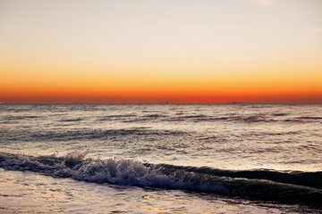 Beautiful view of sunrise in sea. Close Up of waves and beach at sea and colorful sky during sun rise, atmospheric moment. Sunset, dusk or dawn horizon in ocean. Summer vacation on tropical island