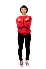 A full-length shot of a Short hair girl with red sweater pointing to the laterals having doubts over isolated white background