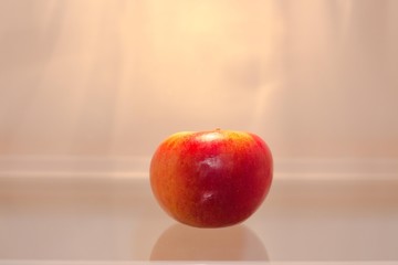 A red and fresh apple is lying on a glass surface on a shelf in the fridge. Apple will remain fresh longer in the refrigerator.