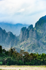 Stunning view of a some limestone mountains illuminated by some sun rays that filter through some clouds. Vang Vieng, Laos.