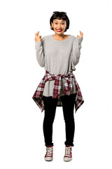 A full-length shot of a Young woman with short hair with fingers crossing and wishing the best over isolated white background