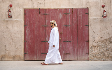 Arab Man walking in old Al Seef area of Dubai - obrazy, fototapety, plakaty