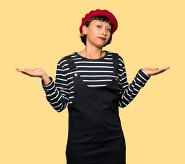 Young woman with beret unhappy because not understand something over yellow background