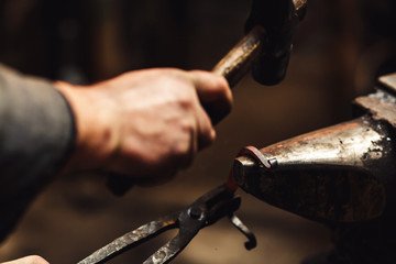 blacksmith makes an artistic forging of hot metal on the anvil.