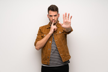 Handsome man over white wall making stop gesture denying a situation that thinks wrong