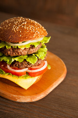 Tasty burger with cheese on wooden table