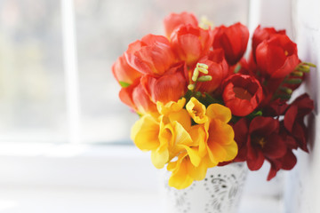 Flower arrangement with tulips and ranunculus on a white wooden floor. Spring flower arrangement in a vase