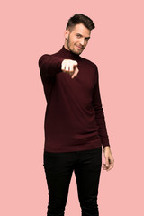 Fototapeta premium Man with turtleneck sweater points finger at you with a confident expression over pink background