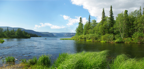 Bright sunny day on the northern lake Seidozero. There are green groves of fir and birch trees  on the banks. Calm, gentle ridges of mountains in the background. With copy space