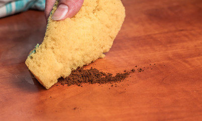 Use of a yellow sponge to clean the kitchen red table . Cleaning sponge