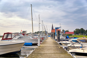 Harbor with sailing boats at the Baltic Sea. In the background the church of Schaprode. Mecklenburg-Western Pomerania, Germany