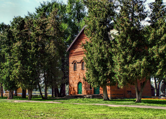 Medieval red bricks building of former church in green park on a sunny summer day