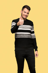 Handsome man with thumbs up because something good has happened over yellow background