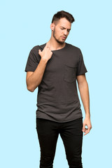 Man with black shirt with tired and sick expression over blue background