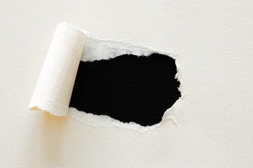 black background with hole in the white paper. Copy space