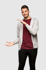Man with sweatshirt holding copyspace to insert an ad over grey background