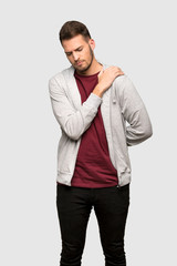 Man with sweatshirt suffering from pain in shoulder for having made an effort over grey background